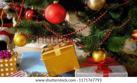Closeup image of lots of gift boxes lying under Christmas tree at living room