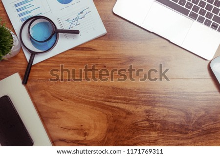 Top view,Business desk with a notebook, report graph chart, pen and tablet on wooden table