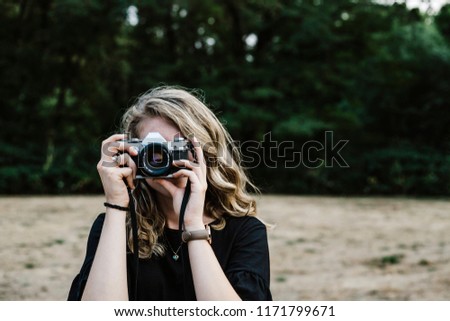Young white woman holding a vintage camera up to her face