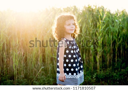 Little beautiful girl jumping and dancing in the rays of the setting sun