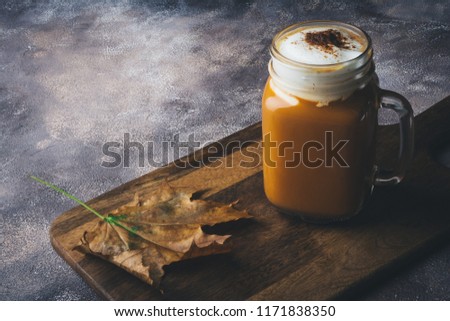 Spice pumpkin latte or coffee with cinnamon. Autumn, fall or winter hot drink. Background with yellow leaves