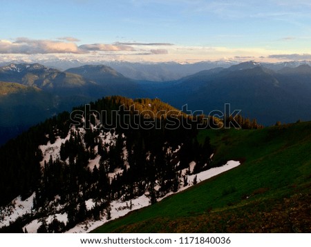 Scenic picture of blue sky and mountains with snow, tress half covered in a shadow 