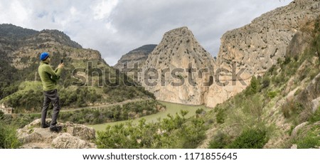 Tourist taking photos of walkways and dramatic cliffs of Caminito del Rey, Spain