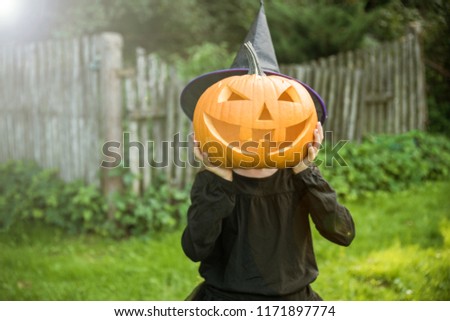 Funny girl with halloween pumpki in garden.