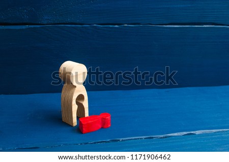 A wooden figure of a woman with a void from which a red child fell. The concept of the loss of a child, abortion of pregnancy, miscarriage. mother lost her child. Deprivation of parental rights. Royalty-Free Stock Photo #1171906462