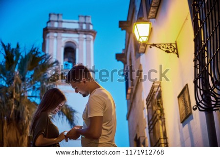 Urban photo of young happy couple looking at cellphone and smiling.