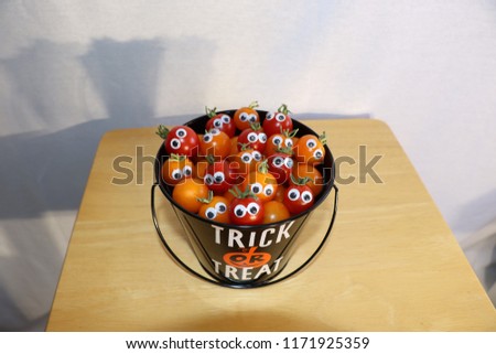 A Halloween trick or treat bucket with mini tomatoes peeking out
