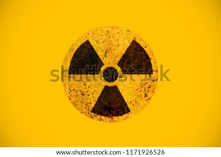Round yellow and black radioactive hazard (ionizing radiation) nuclear danger warning symbol on rusty metal grungy texture and isolated on yellow background.