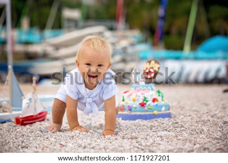 Sweet baby boy, celebrating on the beach first birthday with sea theme cake and sea decoration