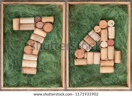Number 74  seventy four  made of wine corks on green background in wooden box
