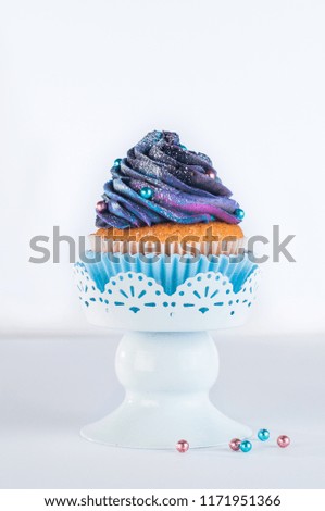 Vanilla cupcake with galaxy dark whipped cream on light background with blank space for text