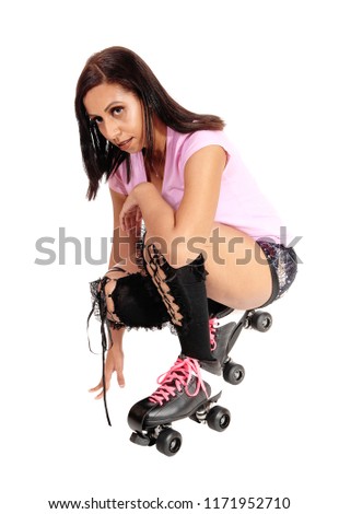 A pretty woman with roller skates and shorts crouching on the floor
resting from her dance, isolated for white background
