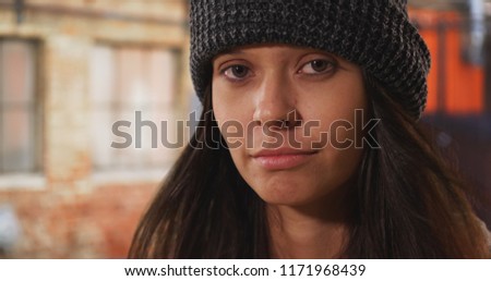 Close up portrait of millennial woman wearing beanie on urban city street Royalty-Free Stock Photo #1171968439