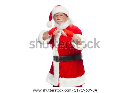 Christmas. Santa Claus with red bandages wound on his hands for boxing imitates kicks. Kickboxing, karate, boxing. Isolated on white background.