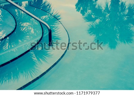 Relaxing turquoise swimming pool scene with a reflection of palm trees. Royalty-Free Stock Photo #1171979377