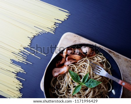 Top view picture of spaghetti spicy sausage on pan above black wooden texture decorate with spaghetti. 