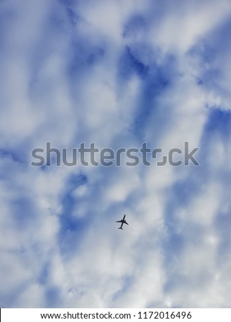 Plane with sky scape. Plane under white clouds and blue sky.