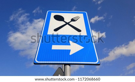 Restaurant sign on post pole, traffic road roadsign, blue isolated dinner bar catering fork spoon signage, right side pointing arrow Royalty-Free Stock Photo #1172068660