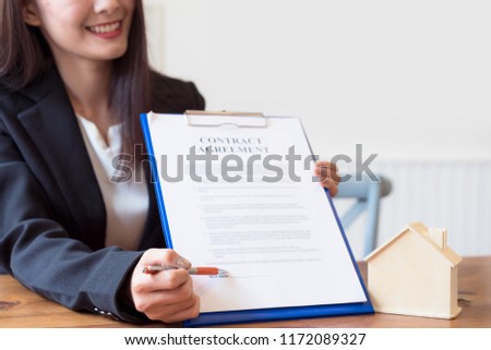 Happy real estate agent showing contract agreement document to the customer before sign at the office. Home loan,moving home or renting property concept.