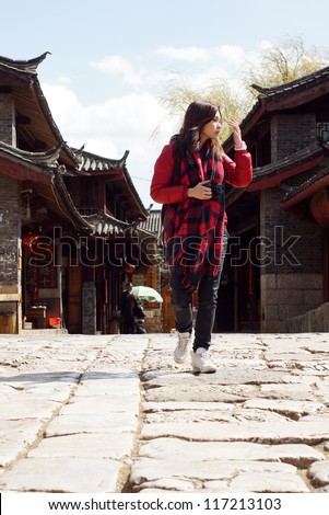 Sight see : chinese travel pretty girl walk on the rock road of historic old town in Lijiang,  Yunnan province with old building background