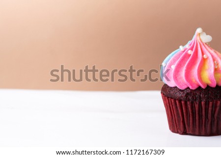 Cute little white heart on rainbow cream cupcake, sweet dessert concept, close up