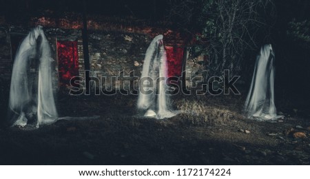 Three ghosts in front of old house with red lights in the forest