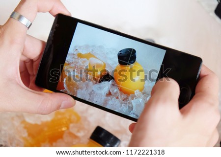 Closeup of orange juice is contained in a plastic bottle with black bottle cap. They are chilled in a box filled with crushed ice to keep them cool. For fresh up in summer. Selfie of food and drinks.