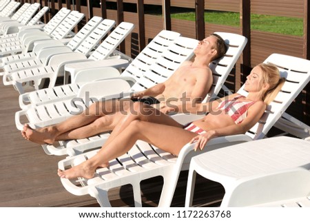 Happy young couple resting on sun loungers at resort