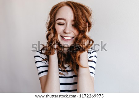 Blissful european woman in casual outfit laughing with eyes closed. Indoor photo of debonair ginger girl expressing excitement.