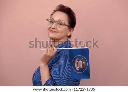 Utah flag. Woman holding Utah state flag. Nice portrait of middle aged lady 40 50 years old with a state flag over pink wall on the street outdoors.