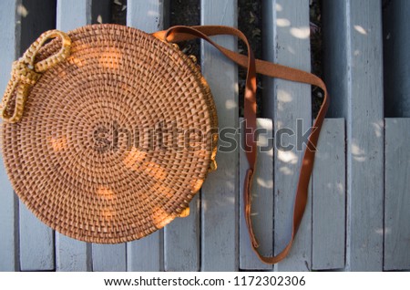 Beautiful wicker handbag with sun spots closeup. The bag lies on the grey bench. Nice bright and colorful picture. 
