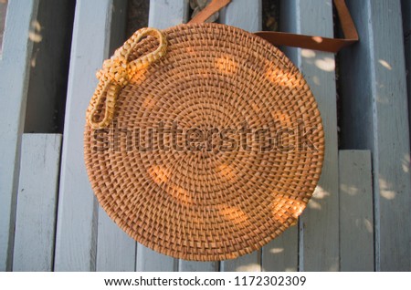 A top view of the modern wicker handbag with light sun spots on it. Stylish circle purse made of the straw. Closeup. A picture with bright colors. 