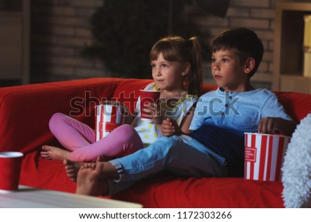 Cute children watching TV on sofa in evening