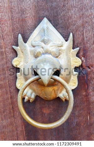 The wooden door with the face of garuda. The animals in the Thai literature circle the whole brass loop. Thai wooden doors are beautiful.