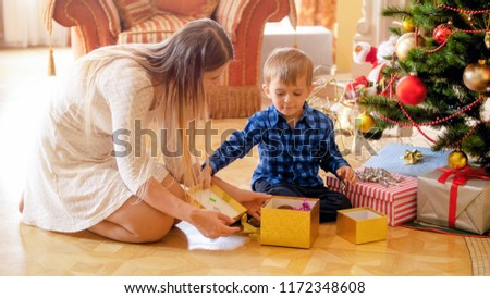Cheerful little boy open Christmas gifts at morning