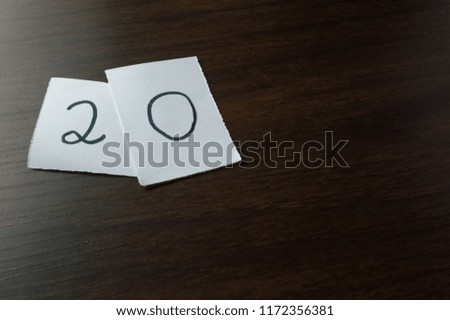 number twenty 20 handwritten on piece of white paper, isolated on wooden background - number concept