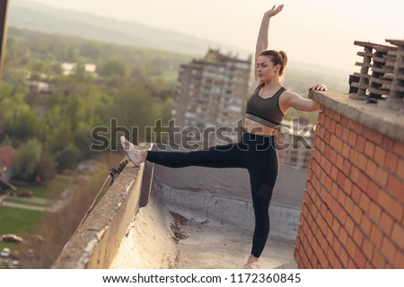 Beautiful young woman stretching before workout on a building rooftop terrace