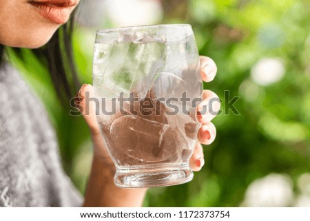 woman drinking cold water with ice in glass in morning