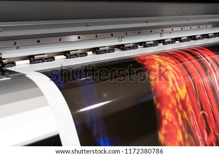 Massive print head processing an oversized glossy color sample before initiating customer orders. Royalty-Free Stock Photo #1172380786