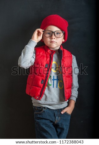 Back to school! Too cool for school. Portrait of child boy in glasses in red hat and vest. Stylish cute kid posing against blackboard. Pupil from elementary school. Education. Autumn clothes