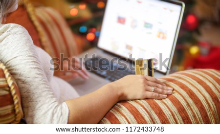 Closeup photo of young woman with credit card and laptop making online orders for Christmas