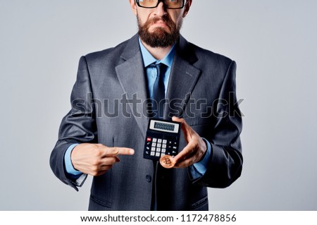 man with a coin in his hand shows his finger on a calculator                             