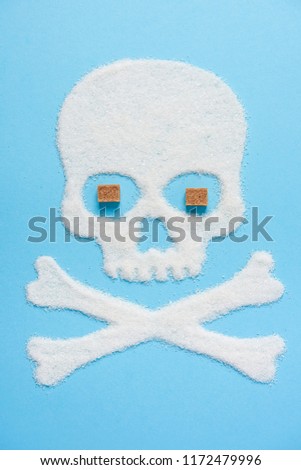 The skull made of sugar with eyes made of brown sugar cubes on blue blue background. Diabetes concept. Sugar Kills. Dieting concept. Unhealthy white sugar concept. Copy space. Space for text.
