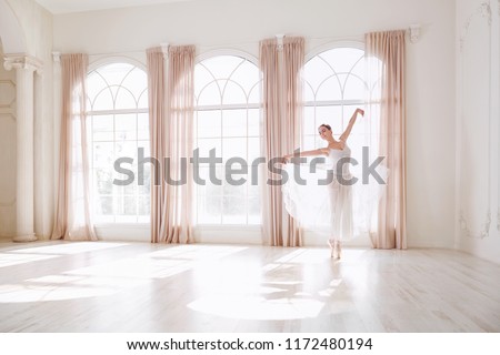 Ballerina dancing in a studio on background window. Royalty-Free Stock Photo #1172480194