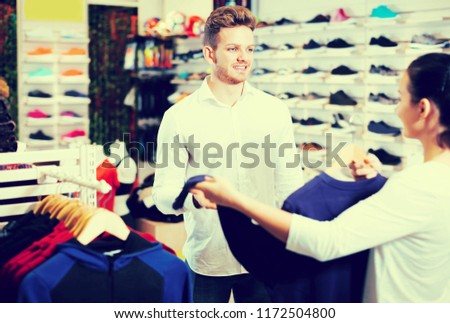Young couple deciding on new sportswear in sports store