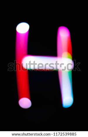 Letter H. Glowing letters on dark background. Abstract light painting at night. Creative artistic colorful bokeh. New Year. Use it for build you own design for book cover, CD, poster or post card.