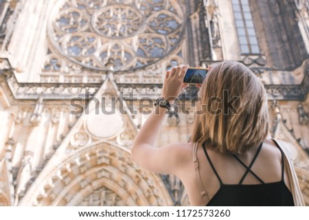 Tourist girl picks up the old Gothic church building on a smartphone. Tourist photographed st vitus cathedral