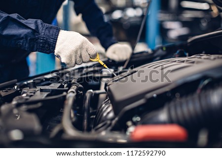 Auto car repair service center. Mechanic checking engine oil level Royalty-Free Stock Photo #1172592790