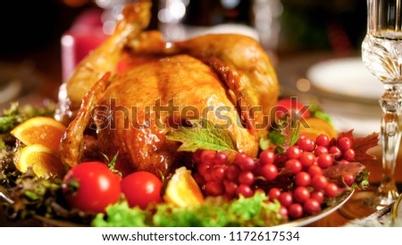 Closeup image of roasted chicken on big dish on Christmas dinner table