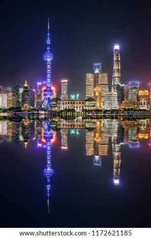 The colorful illuminated urban skyline of Shanghai during night time with reflections in the Huangpu river, China